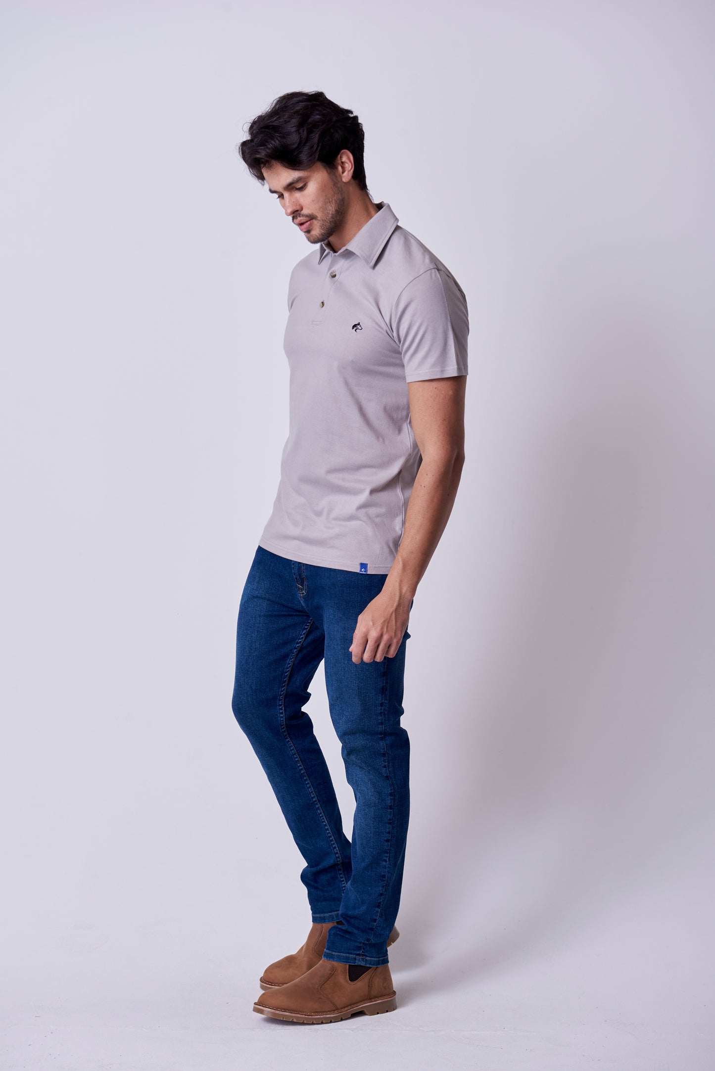 Close-up of the subtle Wolf Rock 'WR' logo branding on the chest of the Grey polo shirt.