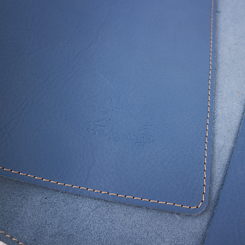 Close up view of the Hedgehogs ladies A4 full grain leather notebook cover in baby blue, showing the subtle logo embossing detail.