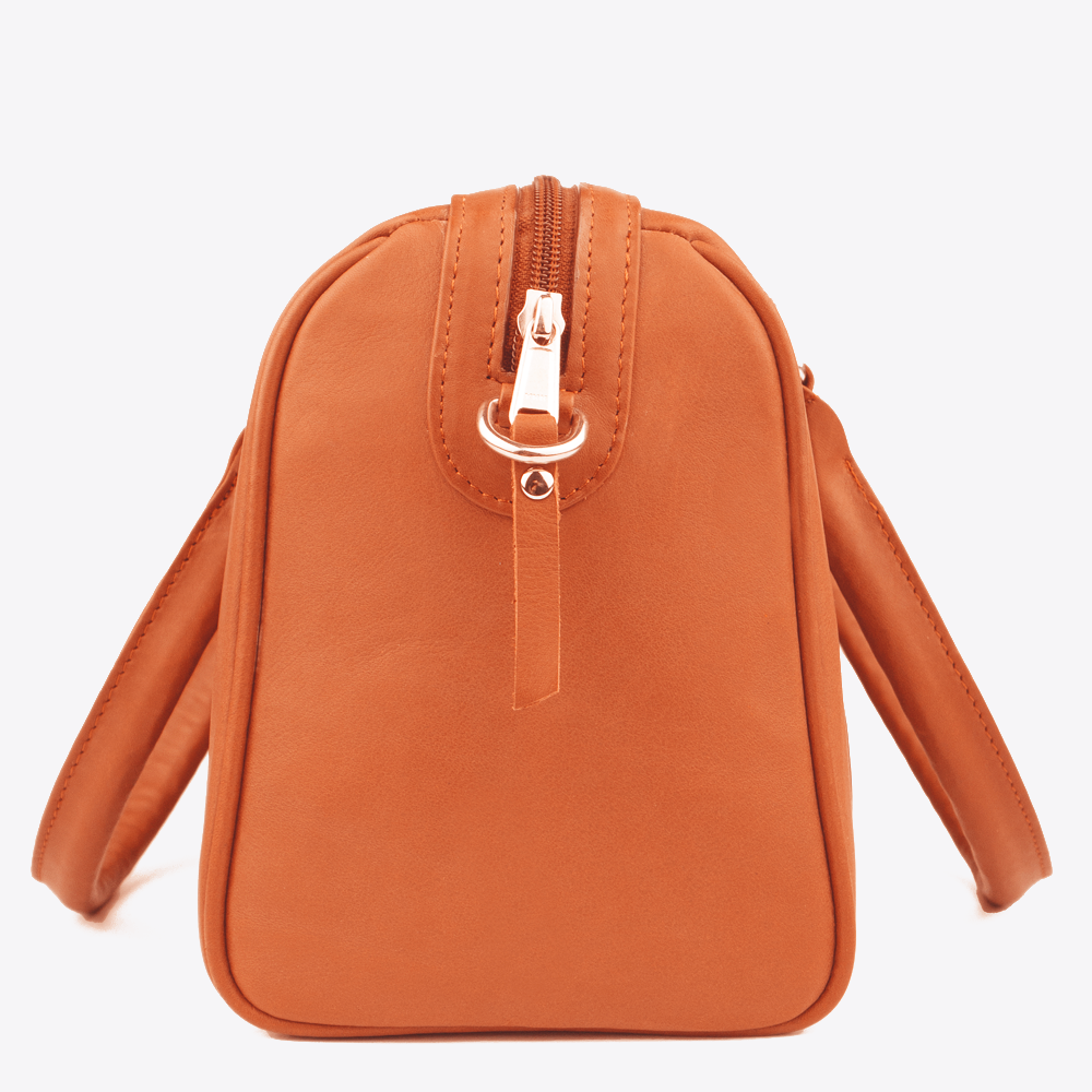 Side view of the Hedgehogs Bowler Bag in coral leather, showing the zip detail and side loop.