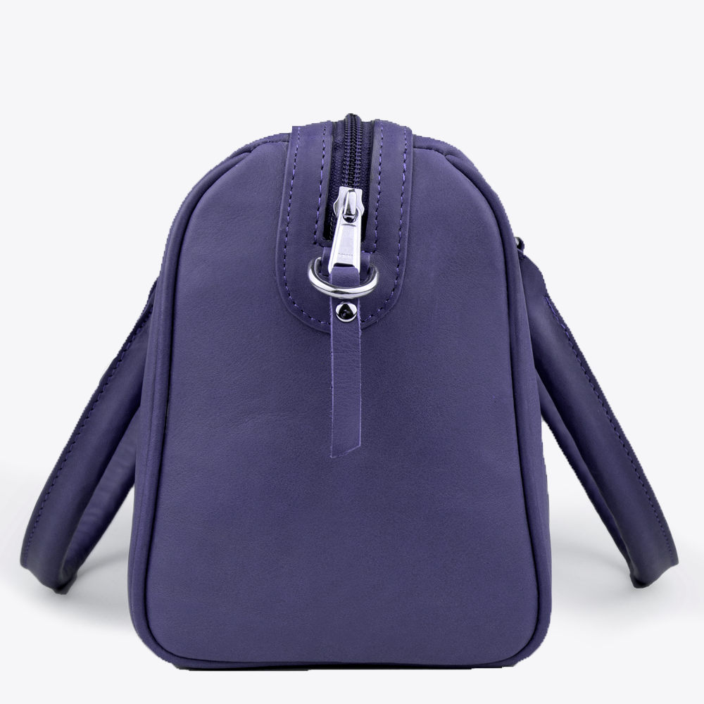 Side view of the Hedgehogs Bowler bag in Indigo leather showing zip closure and side loop detail. 