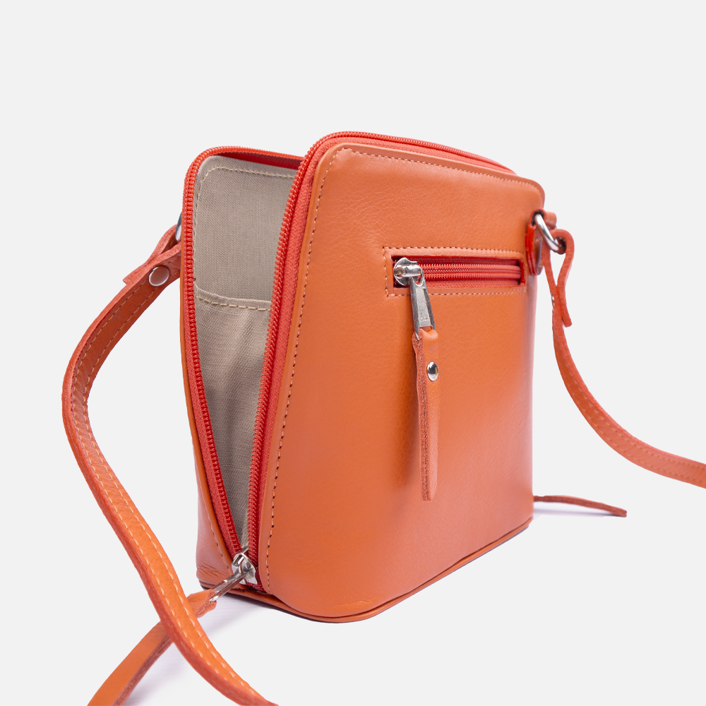 Side profile of the Hedgehogs coral cloth bag showing leather strap, zipper closure and internal lining. 