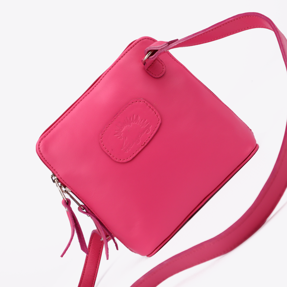 View of the Hedgehogs clutch bag in cerise pink leather showing the front bran embossing and the crossover strap detail