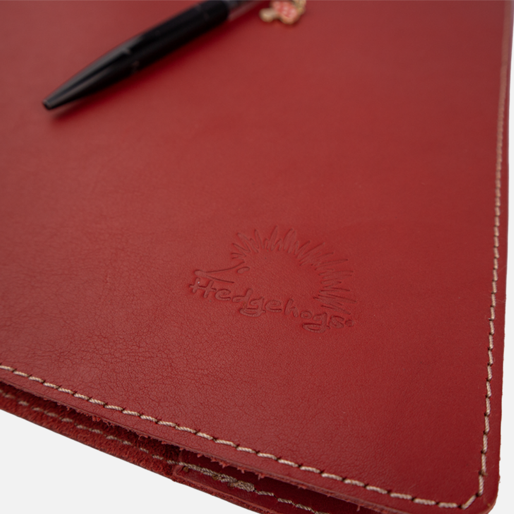 Close up of the logo embossing detail on the Hedgehogs ladies A4 notebook cover in coral full grain leather. 