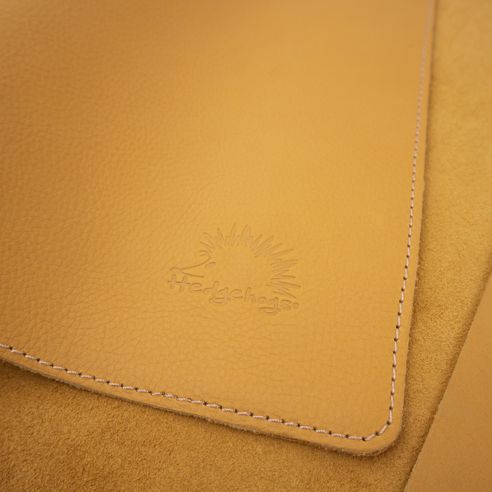 Close up view of the Hedgehogs full grain leather A4 notebook cover in ochre yellow leather, showing the subtle logo embossing on the sleeve cover. 