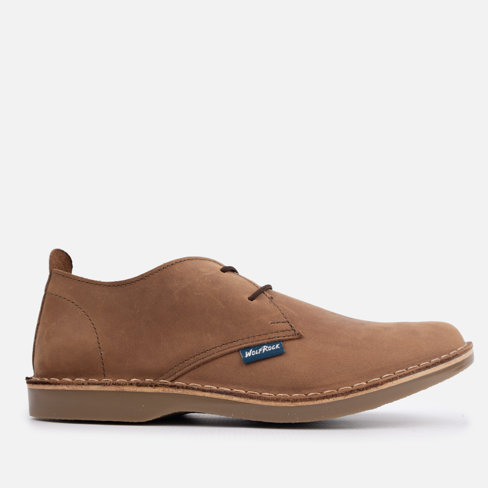 A single brown suede chukka-style shoe shown in side profile on a clean white studio background. A small blue Wolf Rock brand tag is visible near the front side.