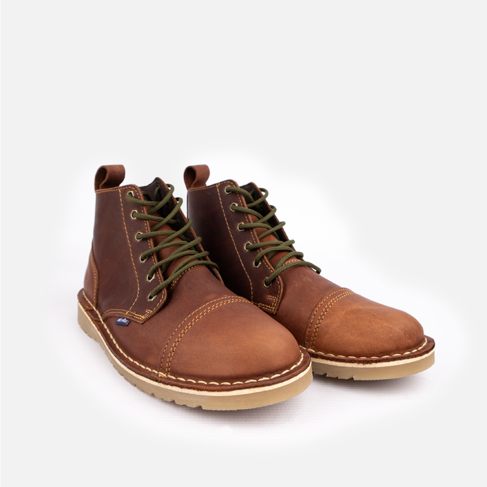 A pair of Wolf Rock Baxter chukka boot in rich cognac leather, showing contrast stitching and green laces. 