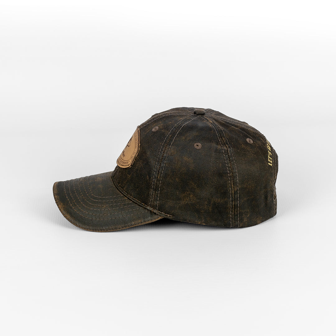 Alternate side profile of the Wolf Rock Brown Oil Skin Cap with leather patch detail. 